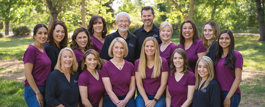 The Forester Dental team, sixteen staff members photographed together outdoors in plum Forester Dental shirts.