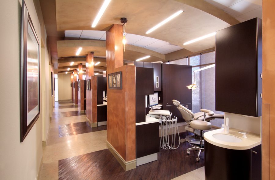 The treatment hallway, lined with patient bays, dental chairs, and warm bronze-toned dividers.